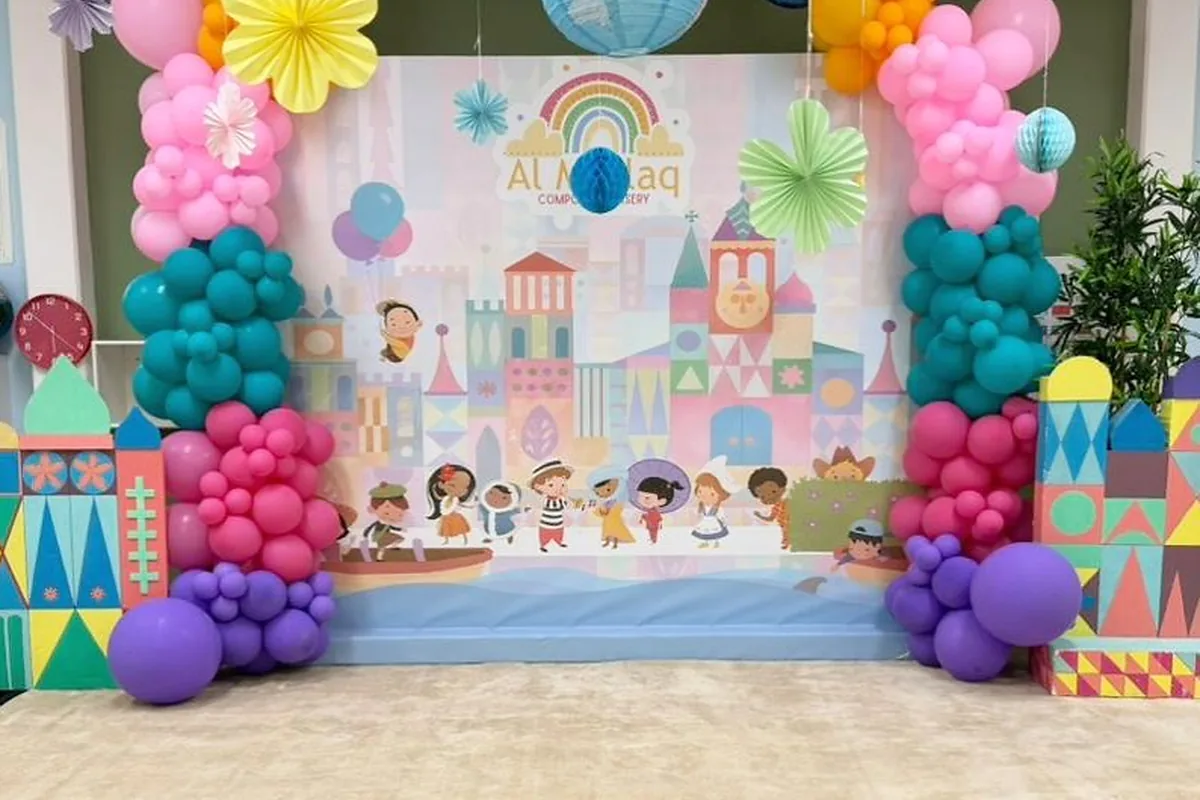 Colorful candy-castle birthday backdrop with layered balloons and playful props