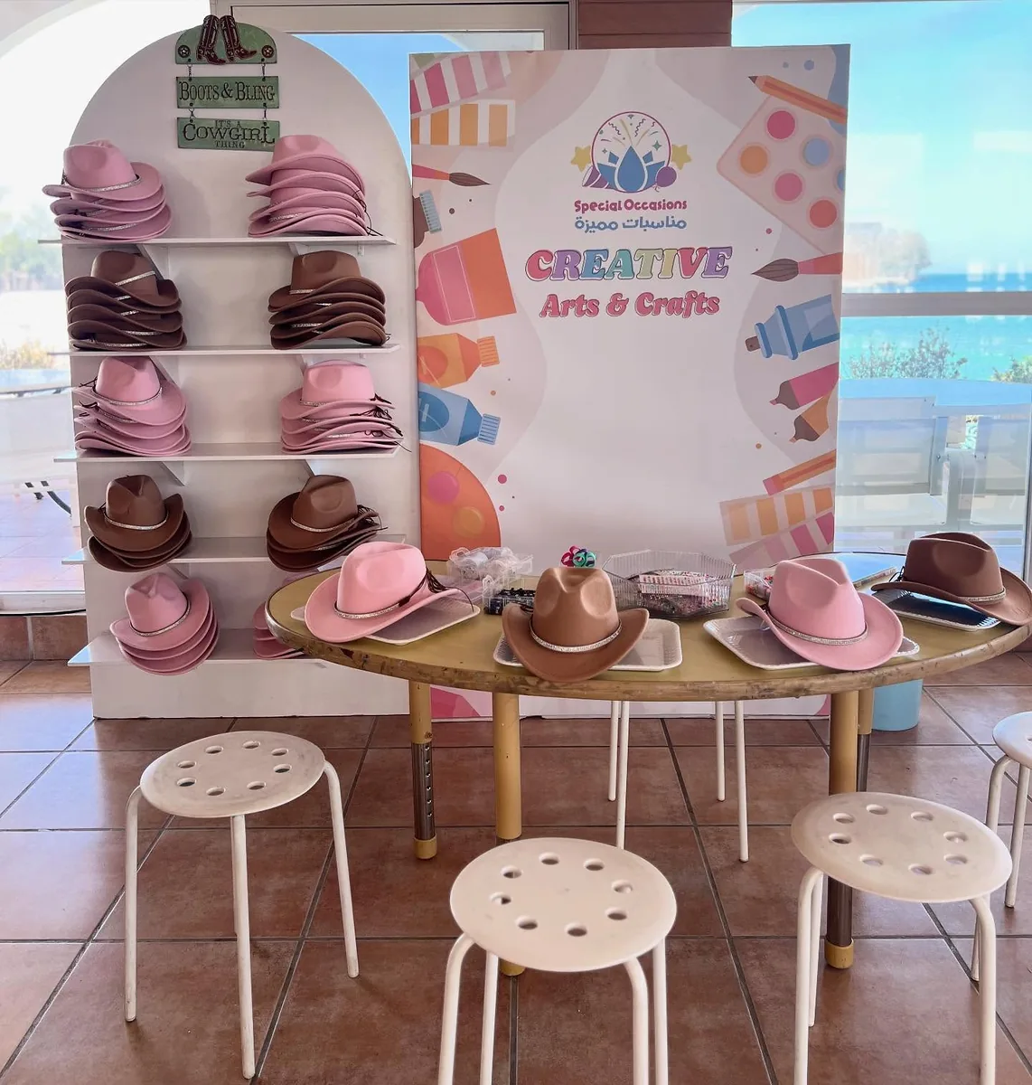 Creative arts station with pastel hats, stools and a branded craft backdrop
