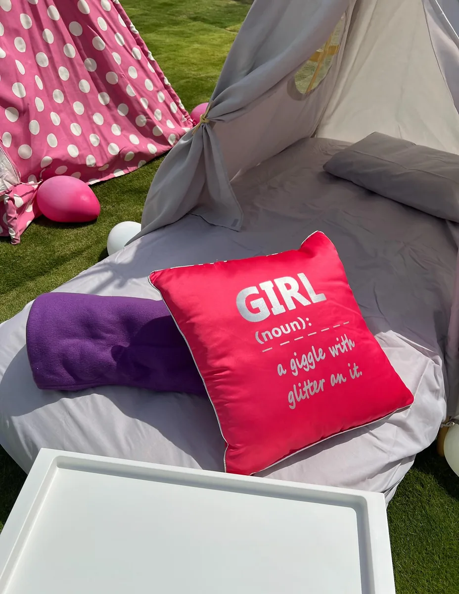 Outdoor teepee lounge with purple cushions and a bright personalized pillow