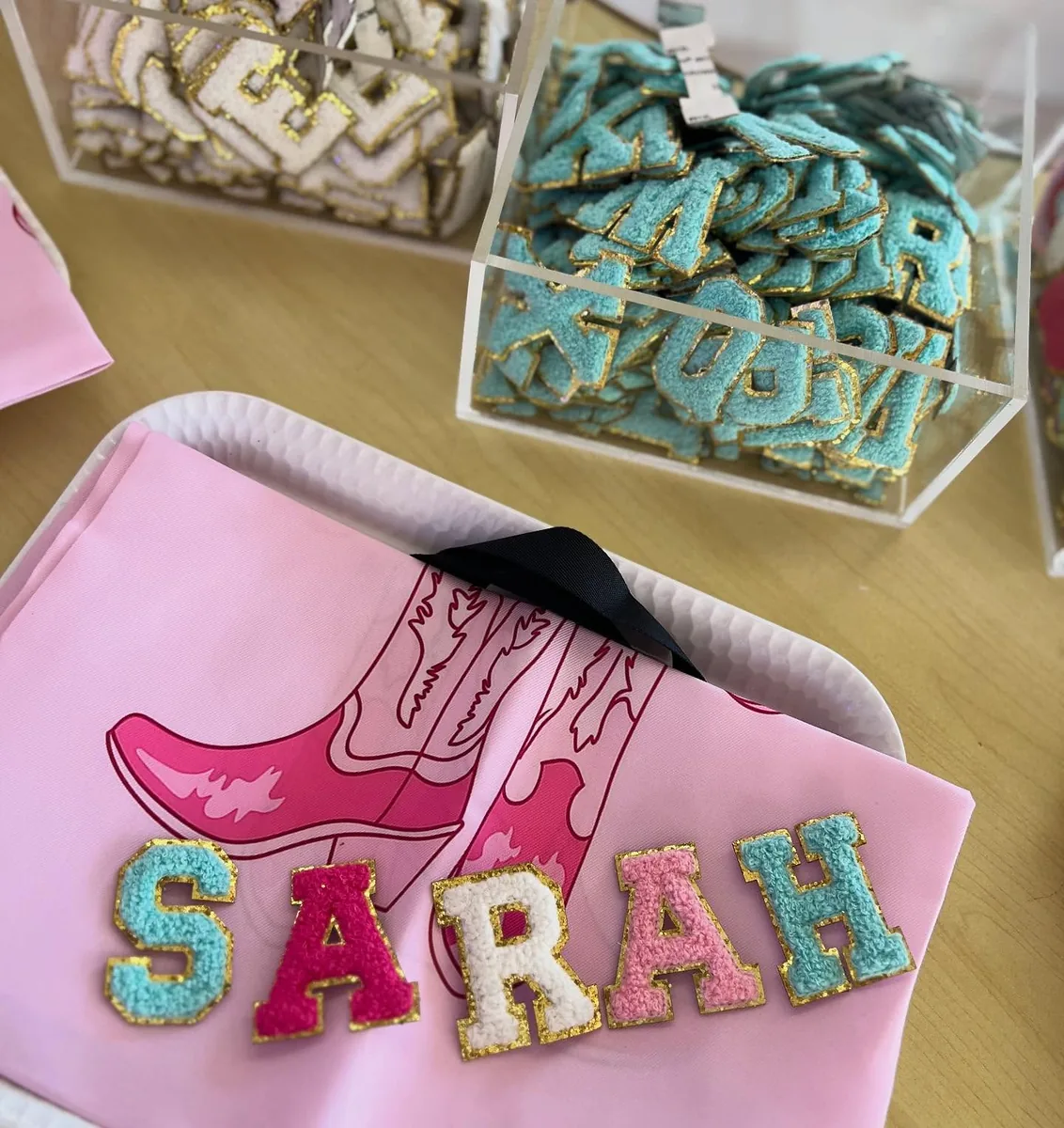 Pink personalized craft tote beside decorated fabric pieces and activity supplies
