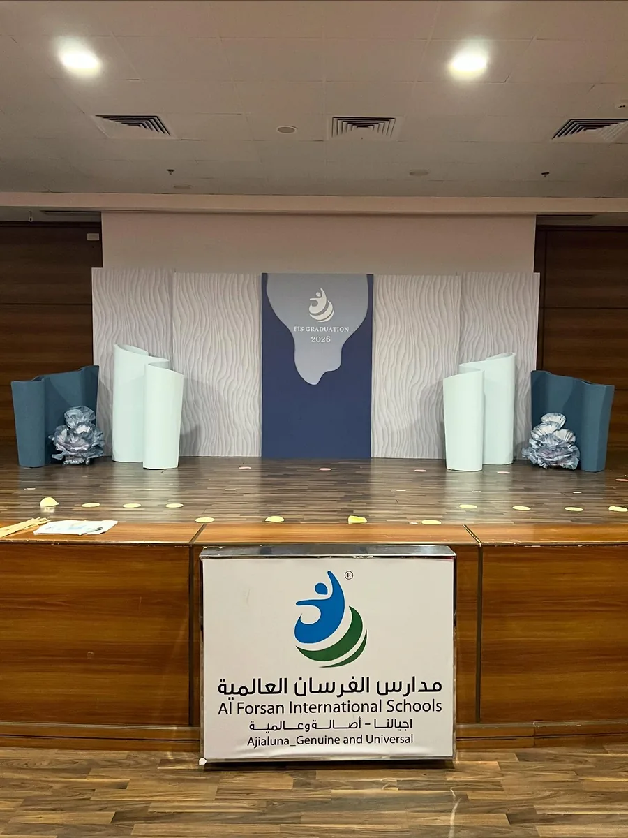 School auditorium graduation stage with navy panels and silver floral props