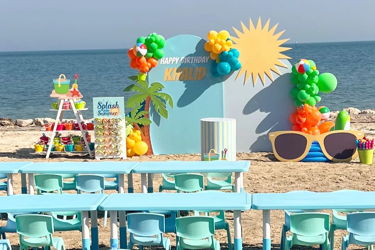 Colorful seaside birthday setup with balloon backdrop and children’s tables in Al Khobar