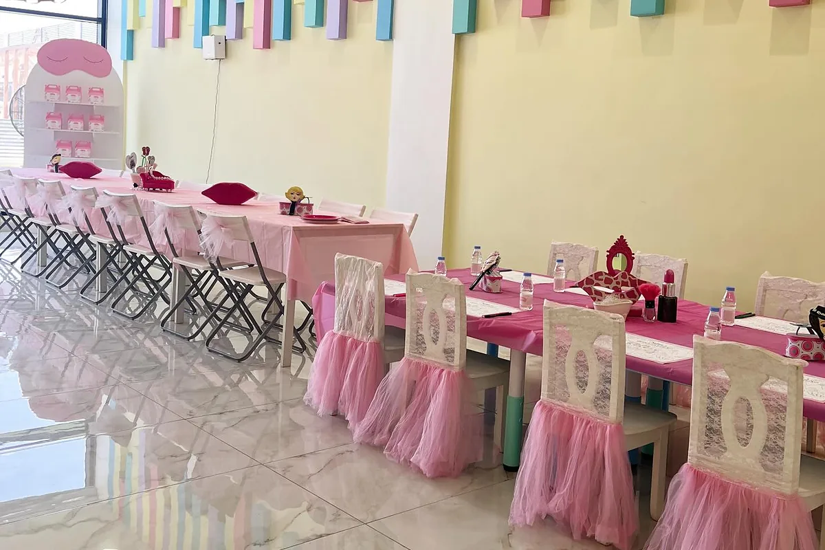 Indoor spa birthday venue with long guest tables and activity zones
